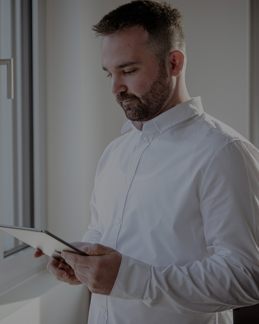 Sympathischer junger Mann schaut interessiert auf das Tablet in seinen Händen.