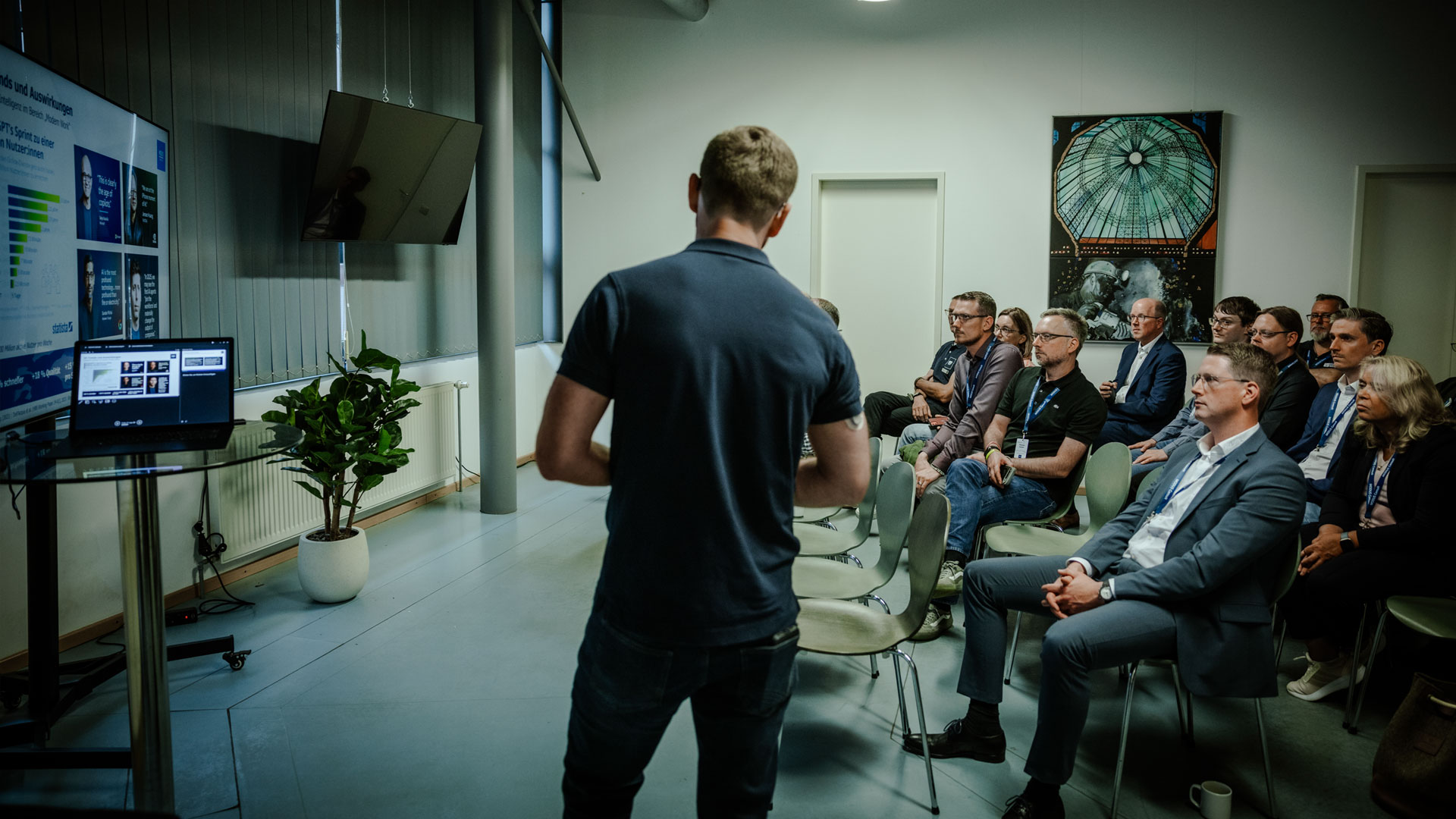 Foto aus einer Breakoutsession, wo man den Speaker von hinten sieht, wie er mit den Teilnehmenden sich austauscht.